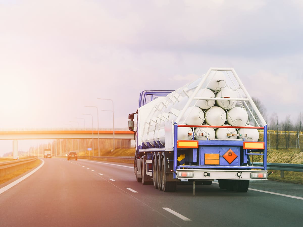 Large truck carrying rolled materials on highway during daytime with clear road markings