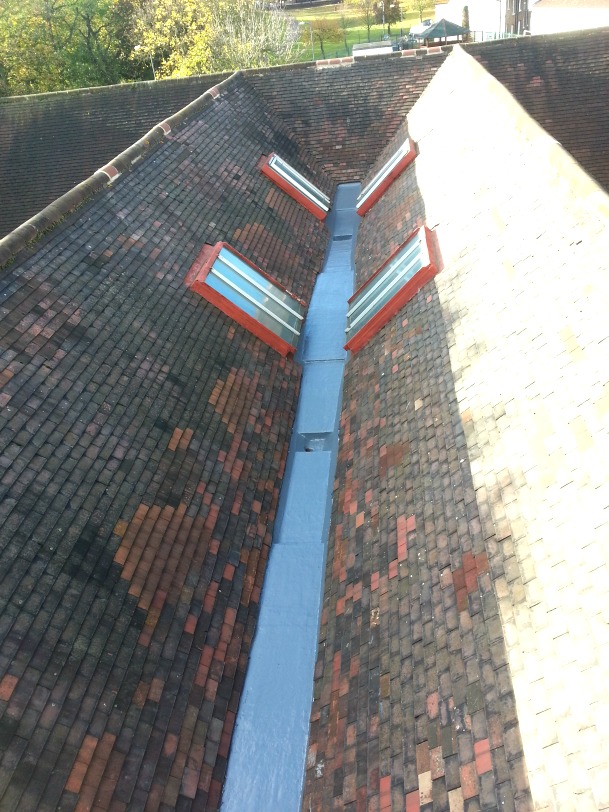 Pitched roof with blue valley and red clay tiles on brick building