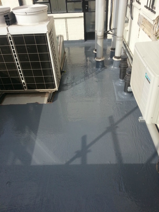 Flat roof with dark gray membrane, HVAC units, and white pipes