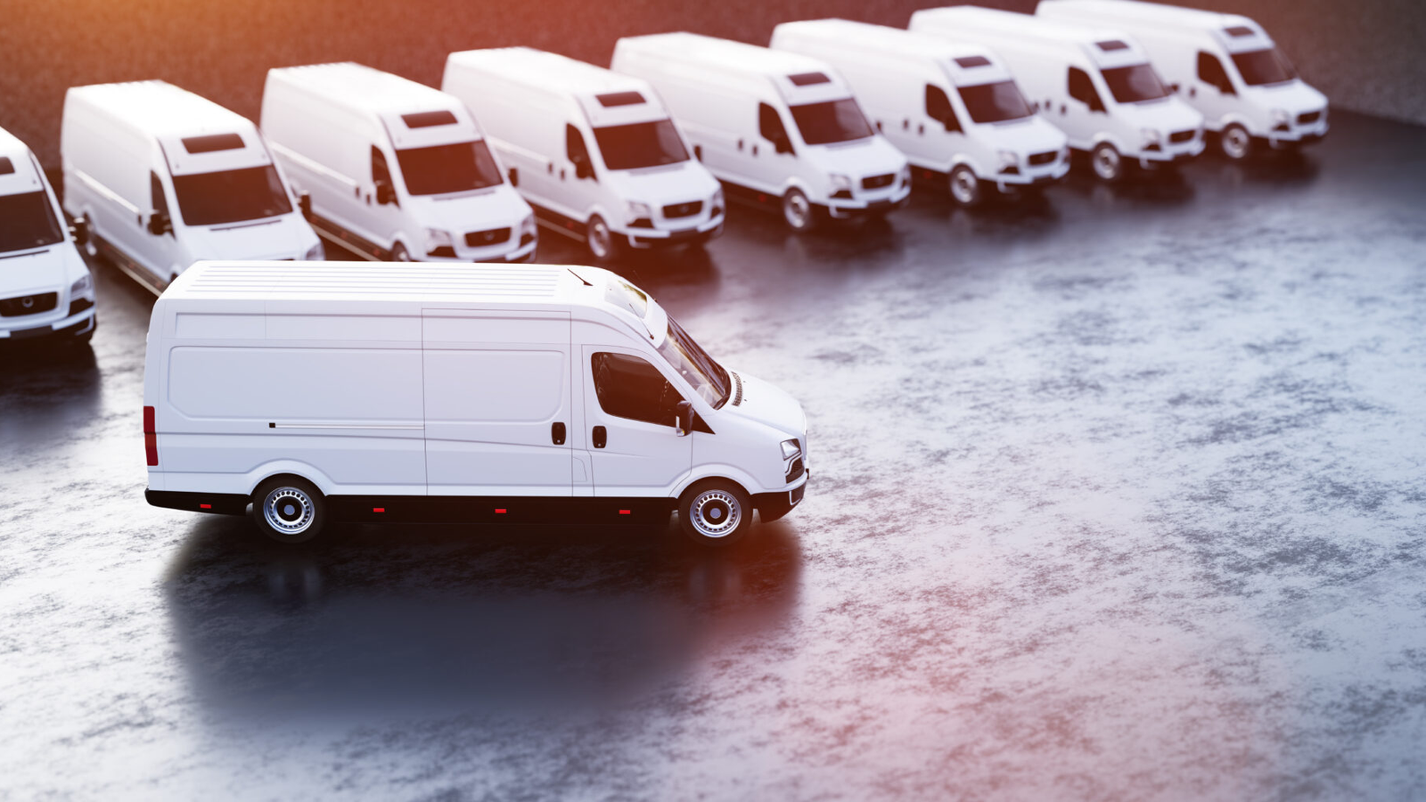 Row of white delivery vans parked on concrete ground