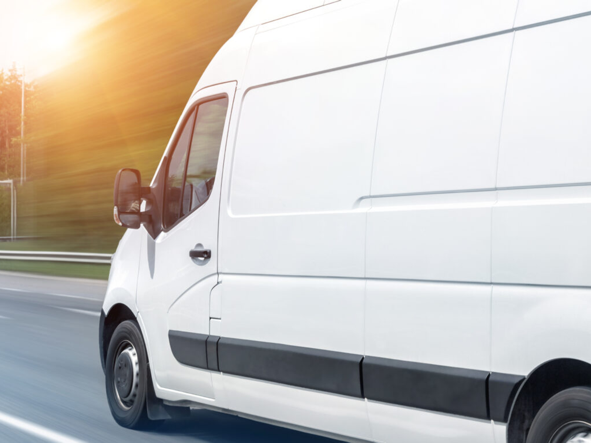 White delivery van driving on road with sunset in background