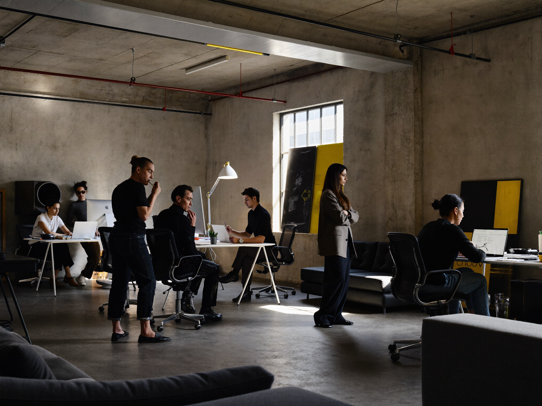 Team of people working in industrial loft office space with concrete walls and yellow accents