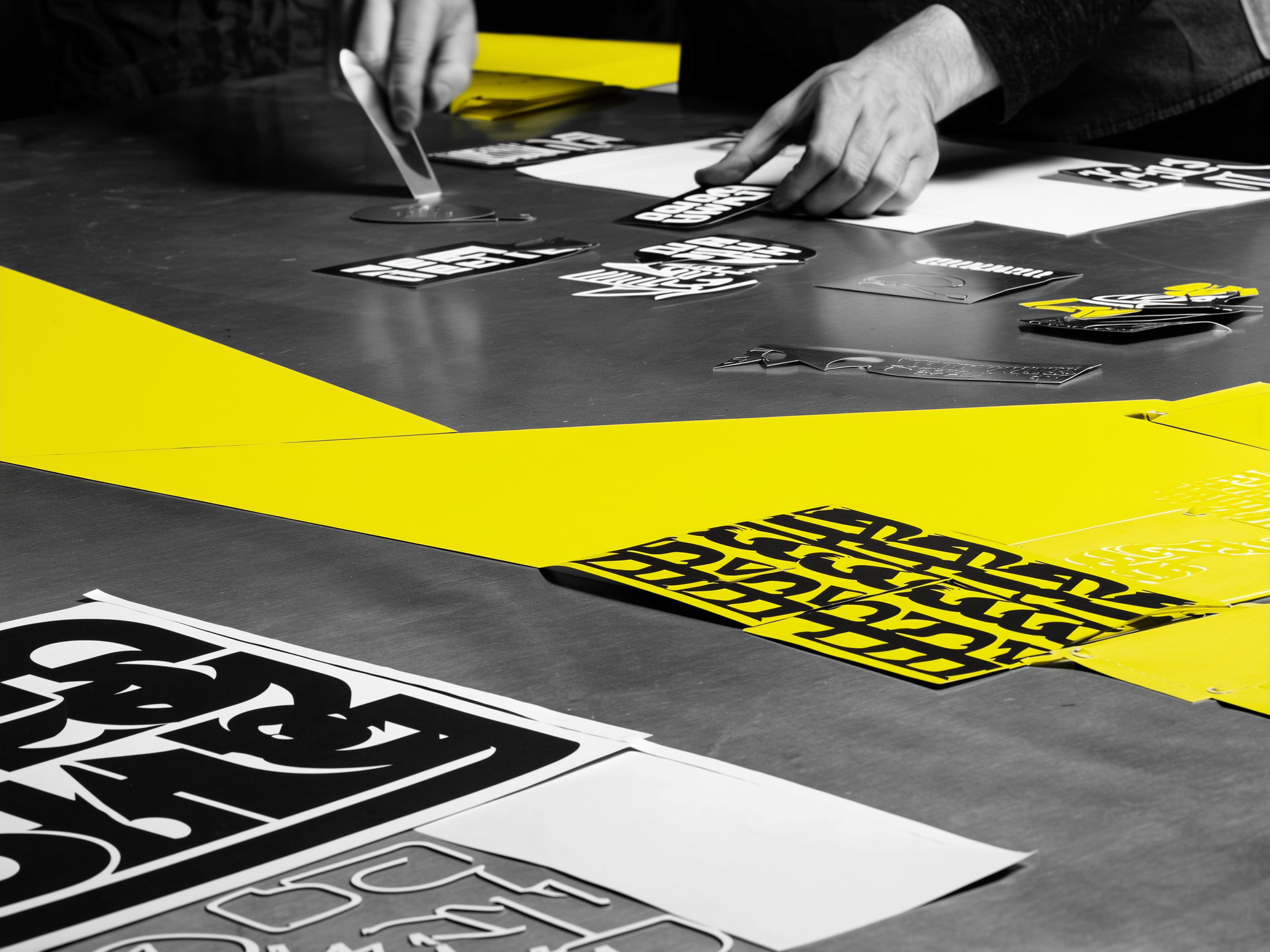 Person arranging design layouts and printed materials on dark table with yellow accents