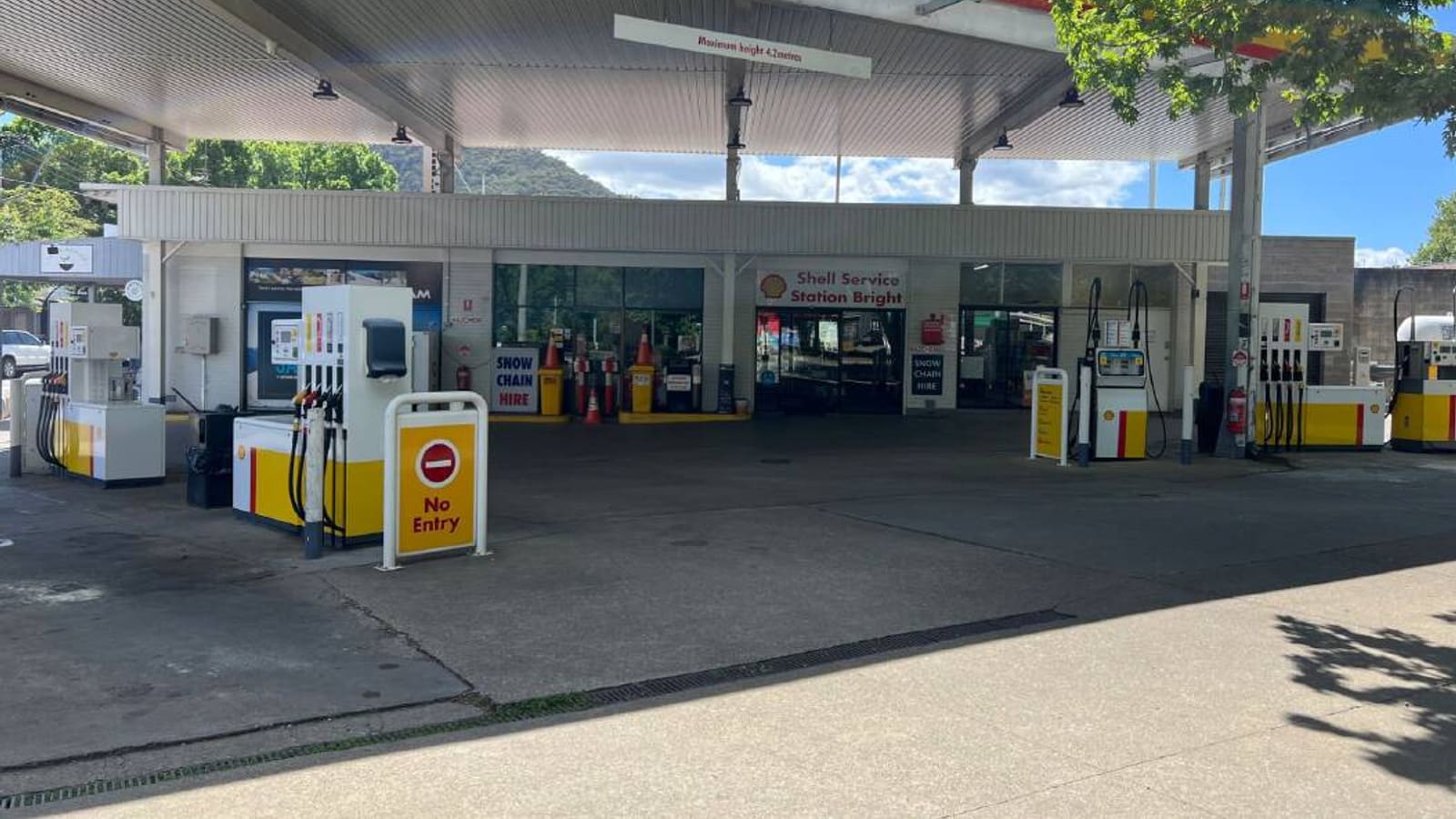 Gas station forecourt with yellow and white pumps and convenience store storefront