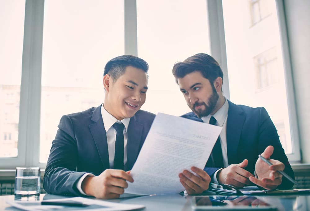 Two businessmen in suits reviewing a document together at a table