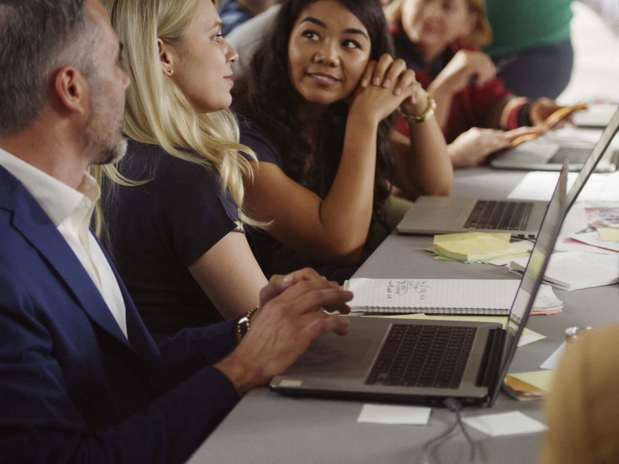 Multiple people sitting at table with laptops during business meeting