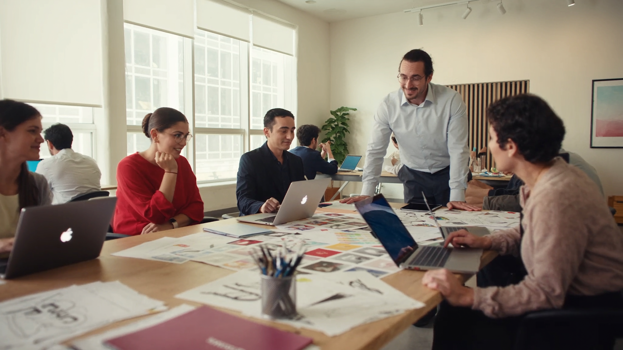 Modern marketing agency workspace with diverse team collaborating around creative projects