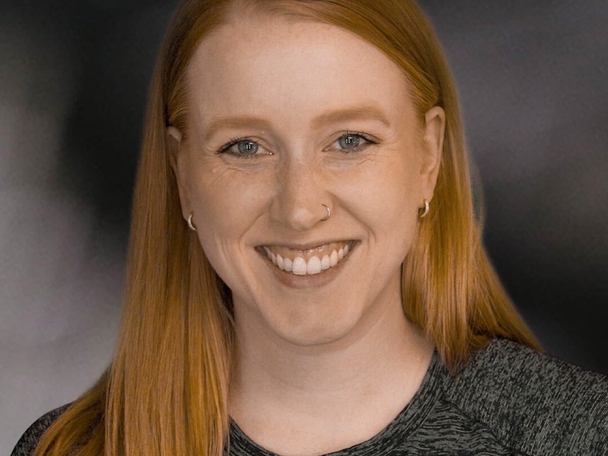 Portrait of a woman with reddish-brown hair smiling at camera