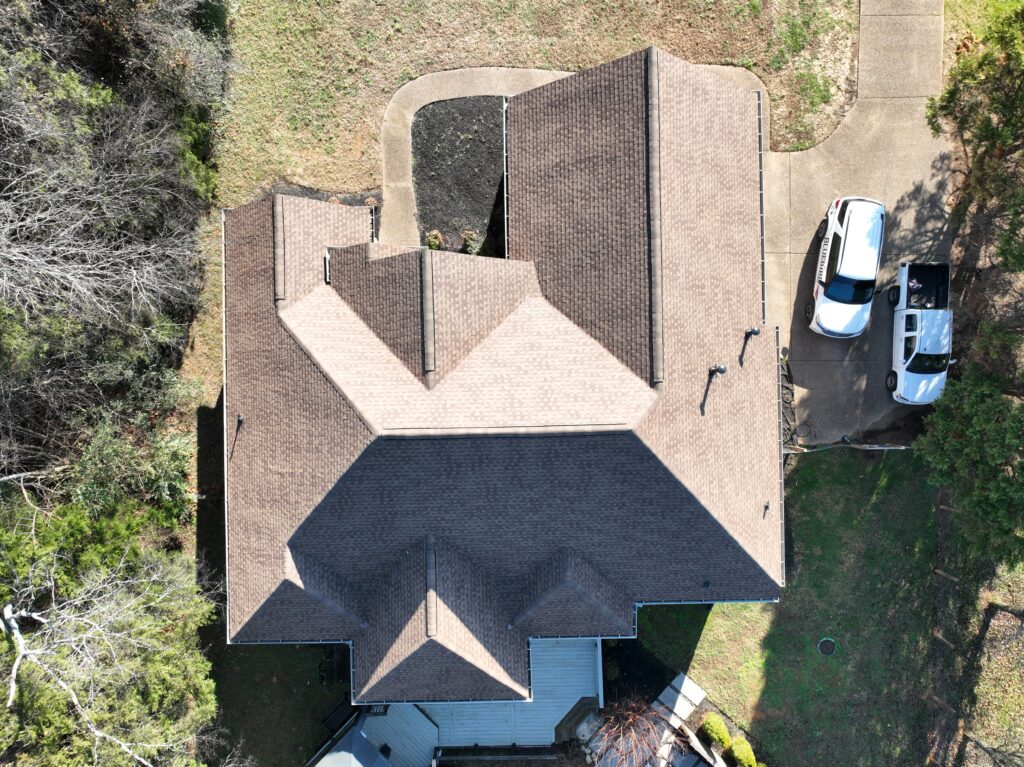 Aerial view of brick residential home with multi-level roof and driveway