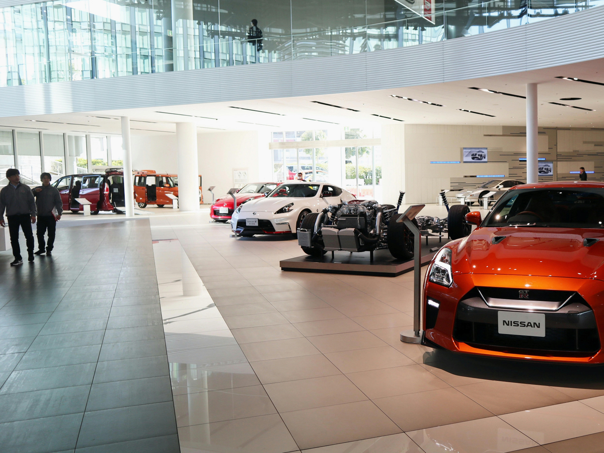 Modern car showroom interior with Nissan vehicles on display and visitors walking