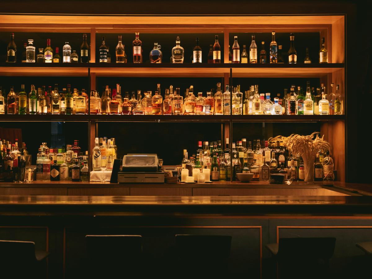 Illuminated bar display cabinet with multiple shelves of liquor bottles and decorative items
