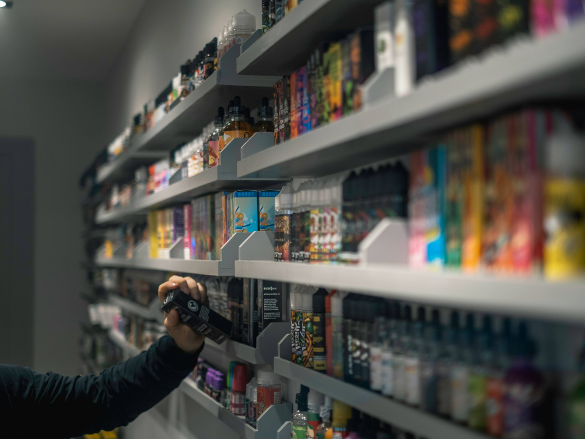 Person's hand reaching toward collectible items on white wall-mounted shelves