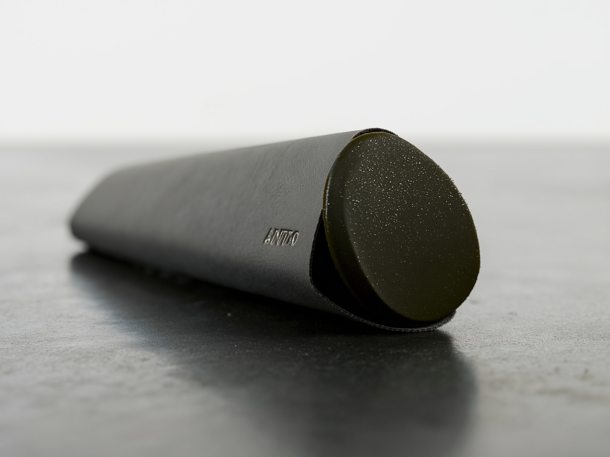 Gray cylindrical device with dark circular end on white surface