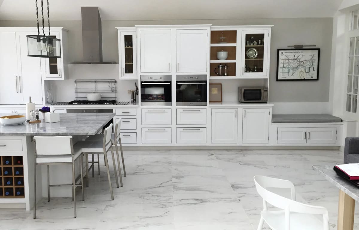 Modern kitchen with white cabinetry, marble countertops, island, and stainless steel appliances