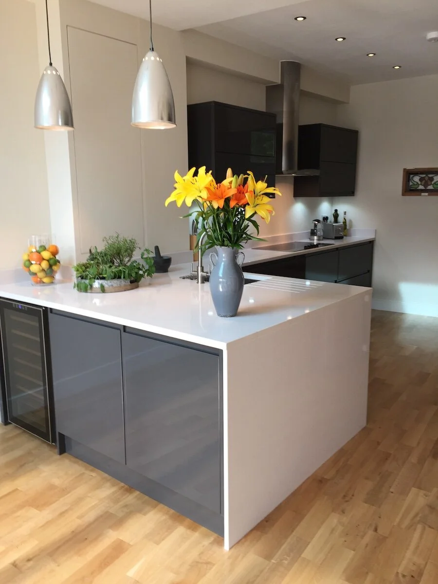 Modern kitchen with white and dark gray cabinetry, pendant lights, white countertop island with yellow flowers
