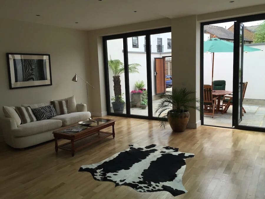 Modern living room with black-framed glass doors opening to outdoor patio areas