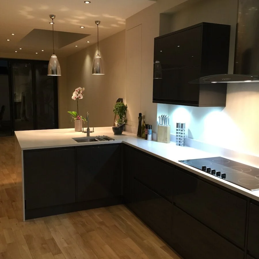 Modern kitchen with black cabinets, white countertop, island, pendant lights, and cooktop