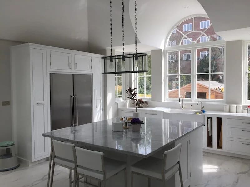 Modern white kitchen with large arched window, dark gray island, and stainless appliances