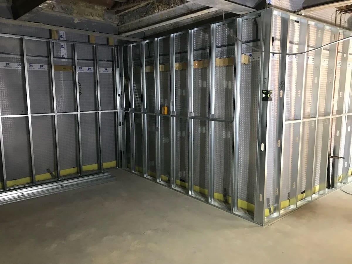 Metal framed storage cages with mesh panels and yellow safety strips on concrete floor
